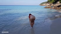 Naked red haired girl bathes on a public beach